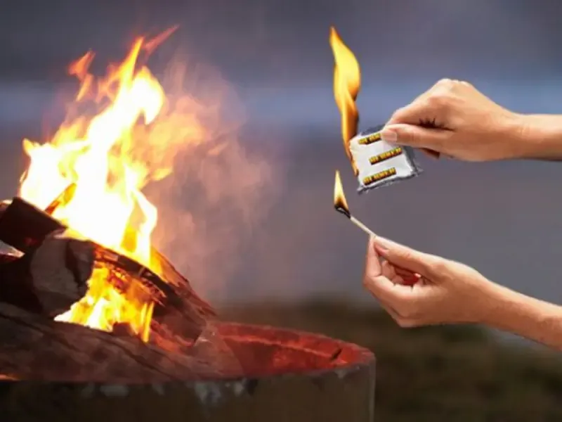 Hand som tänder en eldkorg med en Burner tändpåse